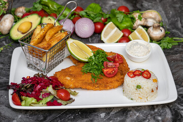 Chicken schnitzel with butter and potato salad on white porcelain plate
