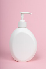 White unbranded dispenser bottle on pink background. Plastic bottle with liquid soap