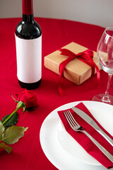 Valentines day dinner concept. Table setting with bottle of wine, silverware, rose, gift box.