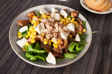 Plate of salad with tuna, corn, tomatoes and arugula