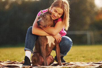 Lying down on a blanket. Woman in casual clothes is with pit bull outdoors