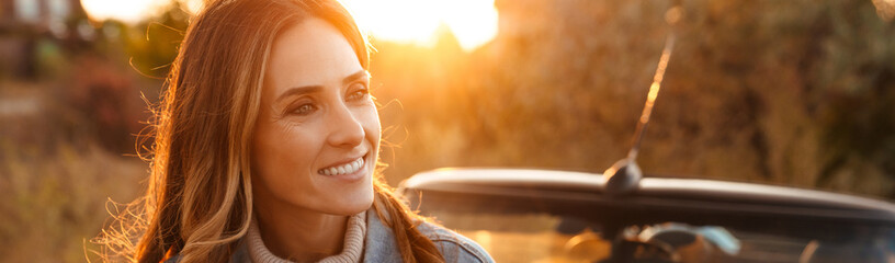 White ginger woman smiling while standing by car