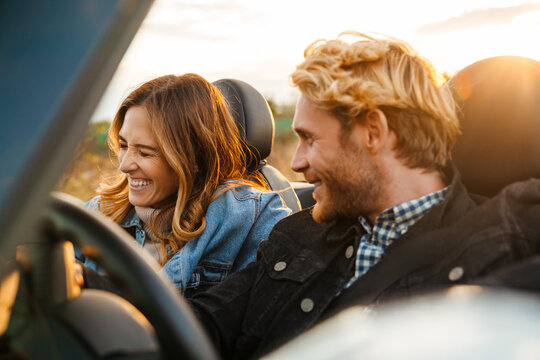 White couple smiling together while driving in car during trip