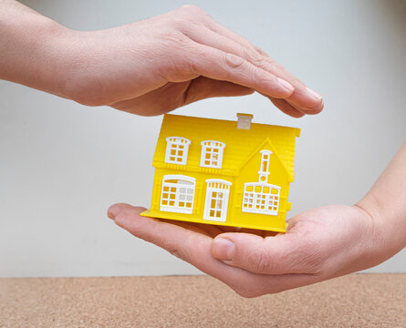 house model between woman's hands.close up. Home Insurance.