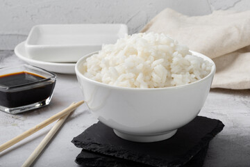 Long-grain boiled rice in a white cup on a light background