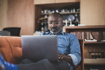 African American adult male using laptop at home on sofa