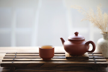 Pottery tea pot and tea cup and pot of dry grass on wooden tray