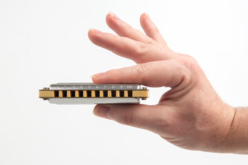 The right hand holds a harmonica on a white background. Classical musical wind instrument.