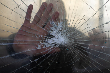 The man presses his hand to the glass. The glass is cracked.