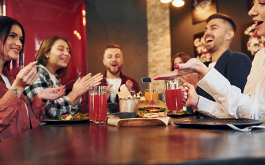 Sitting together. Group of young friends in bar with beer
