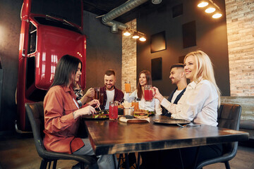 Sitting together. Group of young friends in bar with beer