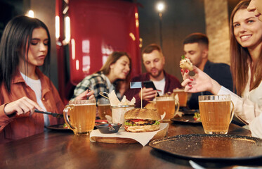 Modern interior. Group of young friends sitting together in bar with beer