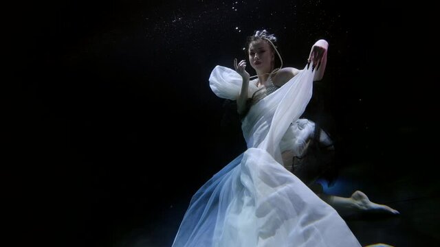 graceful lady is swimming in deepness of dark magic sea, romantic and mysterious female figure