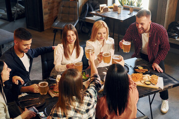 Positive facial expression. Group of young friends sitting together in bar with beer