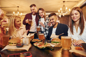 Young friends. Group people sitting together in bar with beer