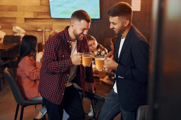 Delicious beer. Group of young friends sitting together in bar
