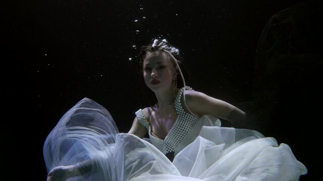 romantic underwater fairy is dancing and floating in sea water, female subaquatic shot