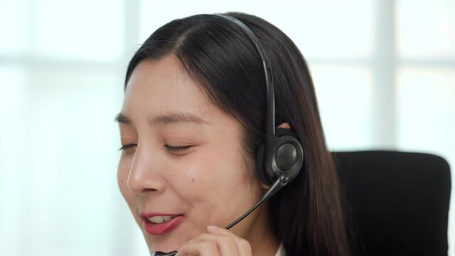 Call center and helpful customer service with online teacher concept. Happy asian business woman receptionist wear headphone video conference calling on computer talk by webcam in online chat