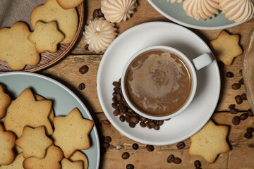 Cup of coffee on a wooden table. Coffee with milk, next to cookies and meringues. Coffee with dessert.