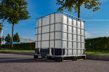 Large plastic tank for liquid. White square barrel for water. Liquid tank in metal lining. Water...