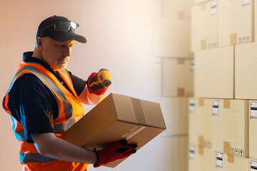 Warehouse worker with data collection terminal. Man scans Barcode on package. Employee fulfillment center. Laser data collection terminal in hand of logistician. Man in warehouse of boxes. - obrazy, fototapety, plakaty