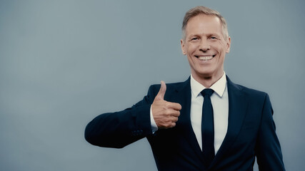 Positive businessman showing like sign isolated on grey.