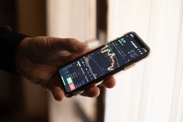 Investor thinking and analyzing graph stock market trading with stock chart data planning, financial and investment concept on smartphone. Side view