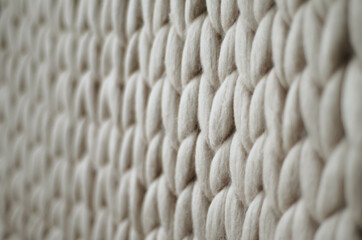 Light grey knitted background. Woolen fabric with pattern of braids. Neutral background of drawing.	