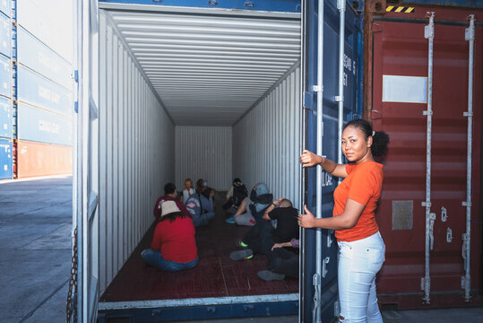 An African Women Opening The Door Of A Container, Inside Of Which Several People Were Sitting, To Human Trafficking And Illegal Immigration Concept.