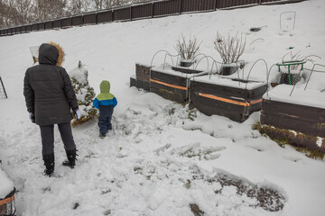 Child with mother play in garden on a frosty winter day. Sweden.