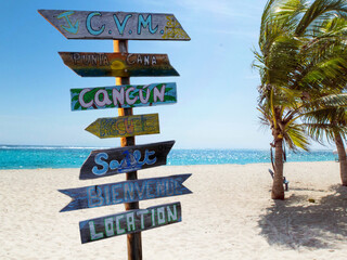Street signpost on the beach indicating directions to different places of the world like Punta Cana...