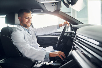 Man in white coat is driving the car