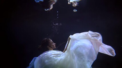 mysterious river fairy is floating underwater in darkness, subaquatic unrealistic shot of young lady