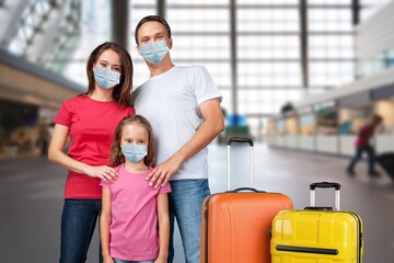 Excited Parents And Little Child In Medical Face Masks Waiting For Flight At Airport Terminal