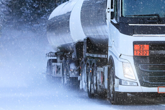 White tanker truck transporting diesel fuel, ADR 30-1202, in heavy snowfall