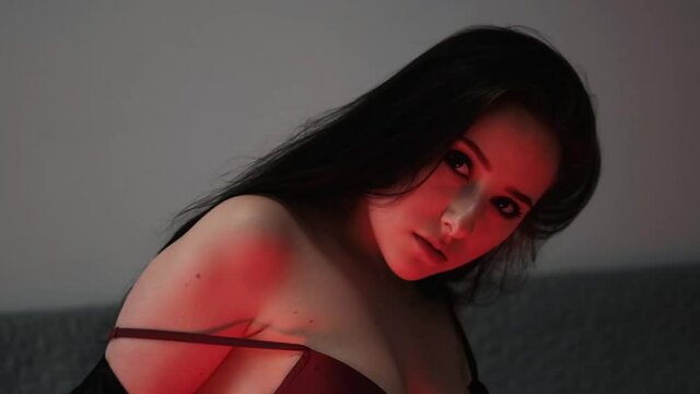 sexy brunette in red underwear and leather jacket posing in red light in dark room.