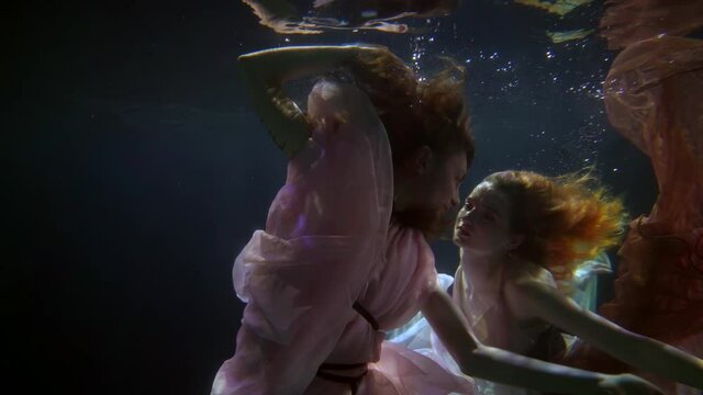 two graceful nymphs of ocean or sea are swimming in deepness, romantic and magical shot underwater