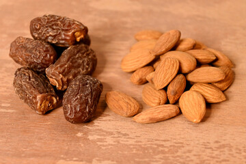 closeup the bunch brown almond nuts with brown synonyms over out of focus brown background.
