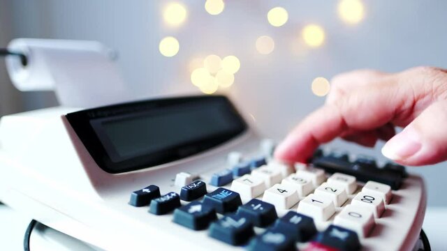 closeup keys and display of the calculator, female hand presses the buttons of the stationary Cash Register, counts and calculates counting operations, small family business concept