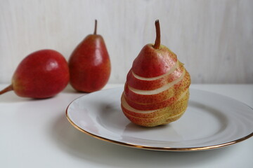 Place the red pear, cut into slices, on a white plate.
