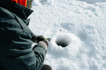 Winter fishing, active leisure, hobby and sport concept. Close-up of fisherman sitting on frozen...