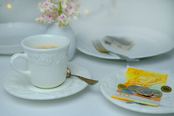 close-up of white plate for money, Swiss francs banknotes and coins, Restaurant bill, cup of...