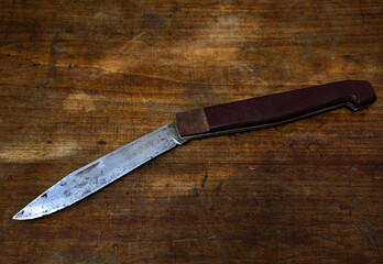 A large folding knife on a wooden table. Criminal showdowns on domestic grounds.