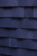 A dark blue architectural asphalt roofing shingles background. A close-up of a dimensional asphalt roofing shingles.