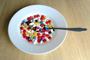 many colored pills, medicine, capsules with powder in a white plate on a light background, the concept of maintaining health, medication treatment, vitamins, dietary supplements, drug addiction
