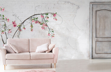 Obraz na płótnie Canvas Pink sofa in the interior. Large potted flowers are a houseplant. Light stylish modern interior.