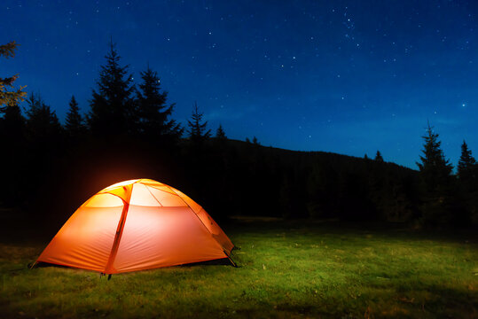 Illuminated tent in night forest