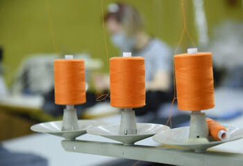 Skeins of thread on a sewing machine, focus in the center. Workshop for the production of clothing.