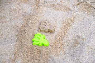 green plastic mold for children to play on the sand, fun in summer with sand on seashore, in sandbox, on playground, beach, concept of development of fine motor skills, summer vacation