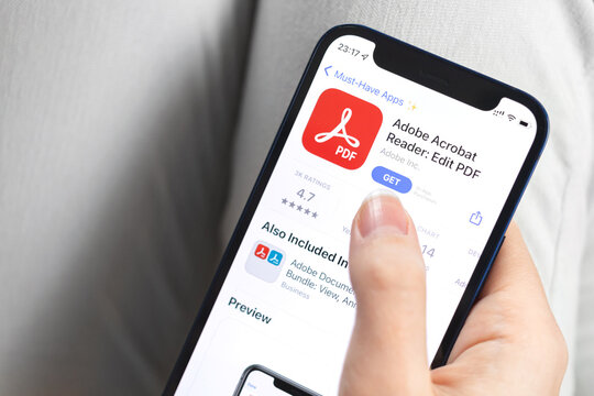 Adobe Acrobat Reader app icon close-up. Woman with application on Apple iPhone 12